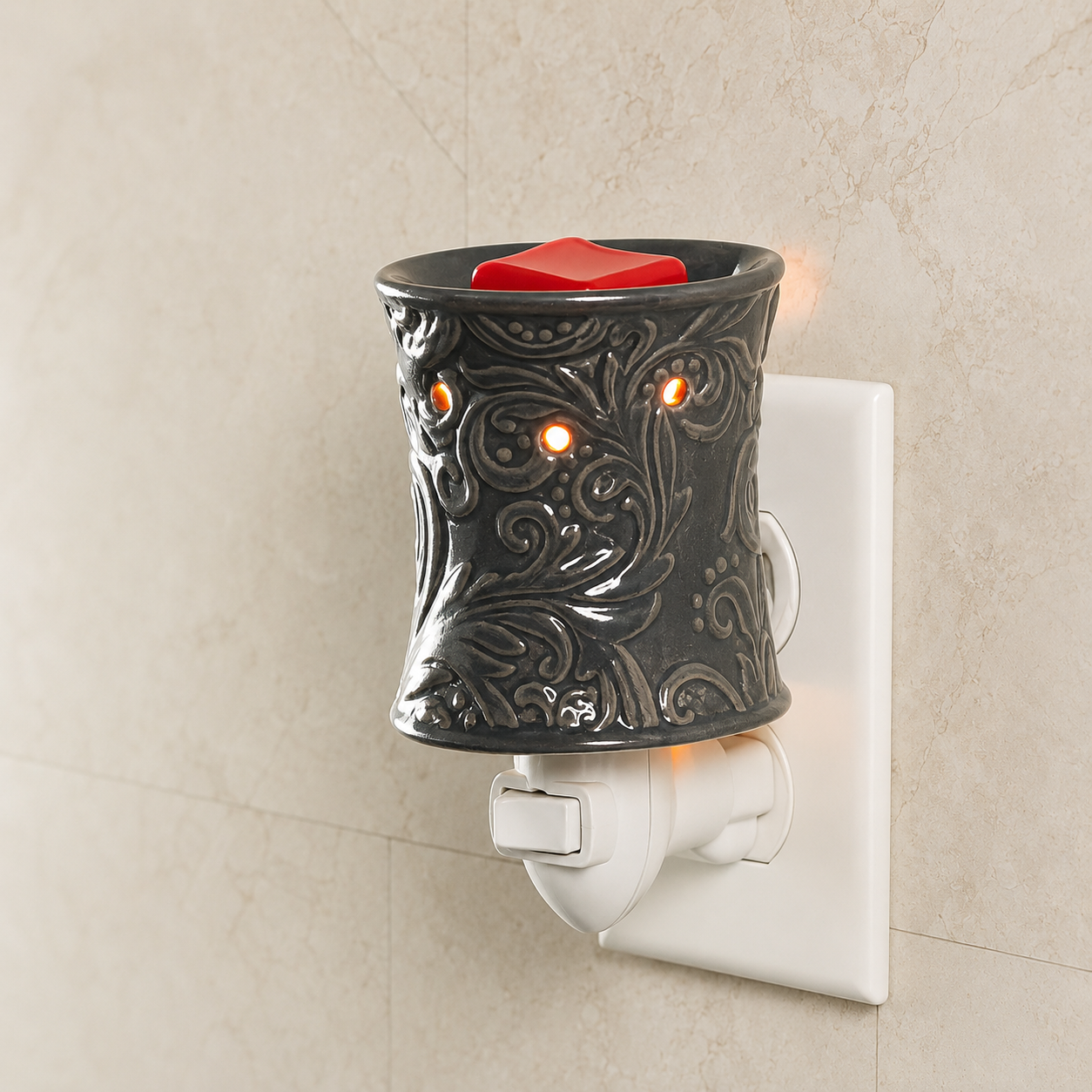 Decorative wall-mounted wax warmer with a red candle on a beige wall.