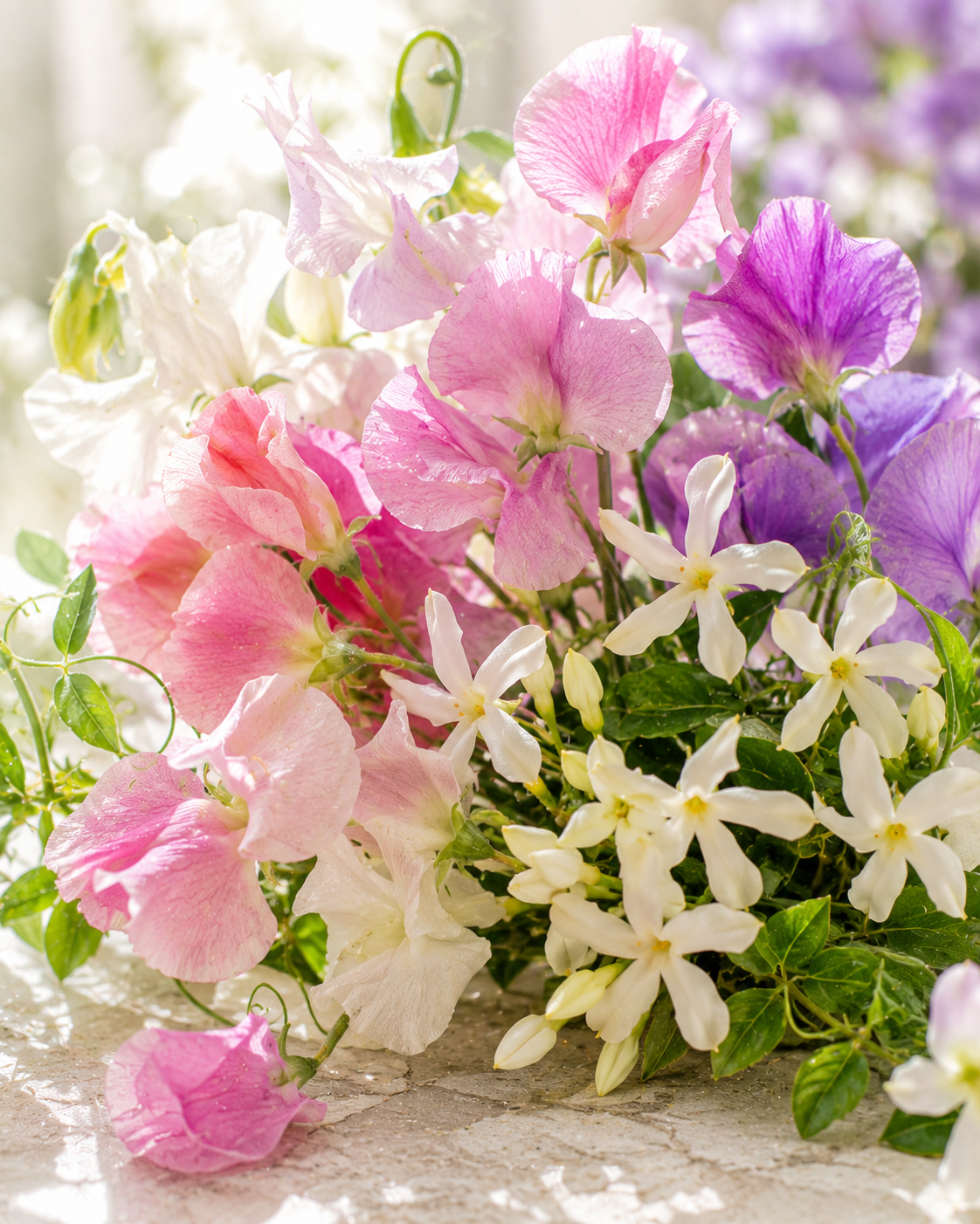 Bouquet of pink, white, and purple flowers with green leaves on a textured surface.